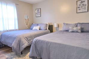 Une chambre avec deux lits, une table de chevet, une lampe et des œuvres d’art murales.