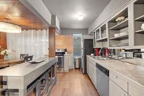 A modern kitchen with a central island, built-in appliances, and a dining area with a wooden table and chairs.