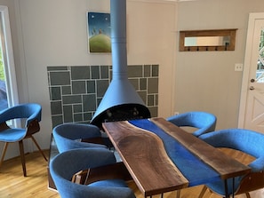 Un comedor con una larga mesa de madera, sillas tapizadas en azul y una estufa cónica azulada.