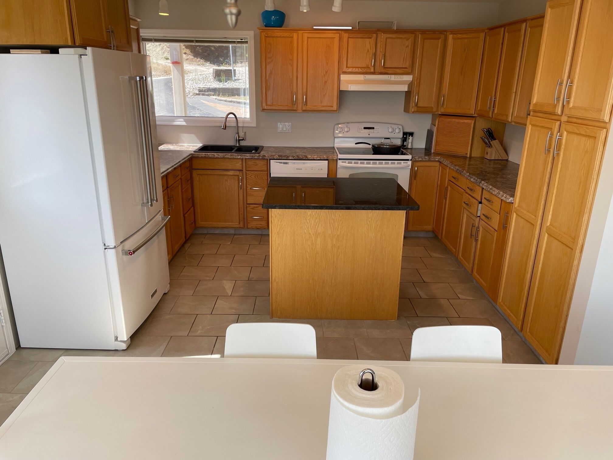 A kitchen with wooden cabinets, a white refrigerator, a stove, and a sink.
