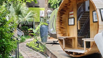 A wooden pod-style room with a built-in fan, a staircase, and a view of a lush garden.