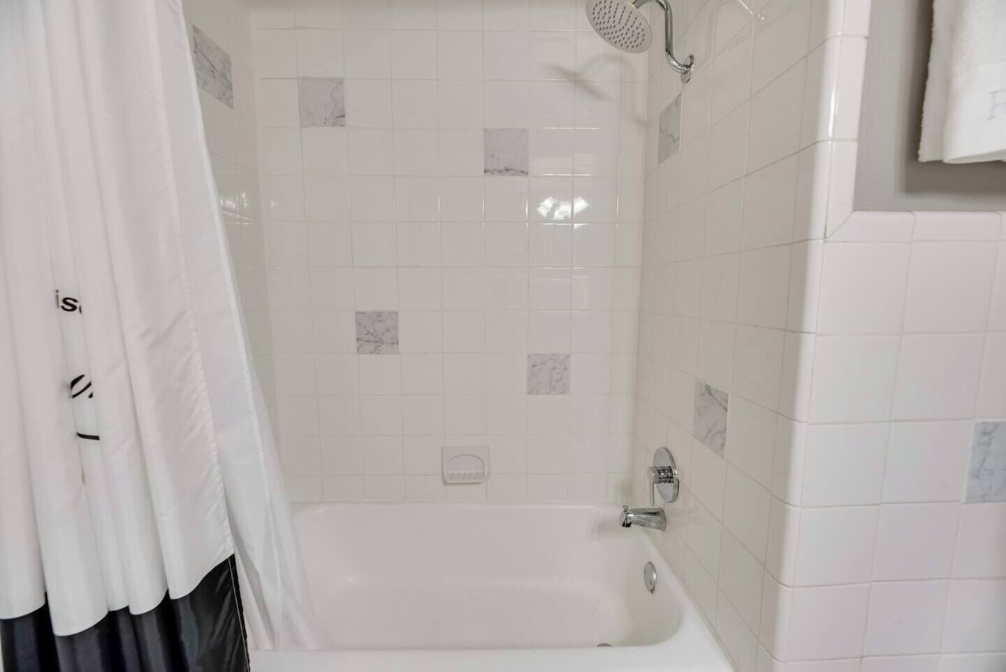A bathroom with a bathtub, shower, and tiled walls.