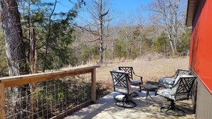 A wooden deck with a metal railing, two chairs, and a small table. - Cozy cabin 16 miles from Razorback Stadium great for game weekends. No pets. (Elkins)