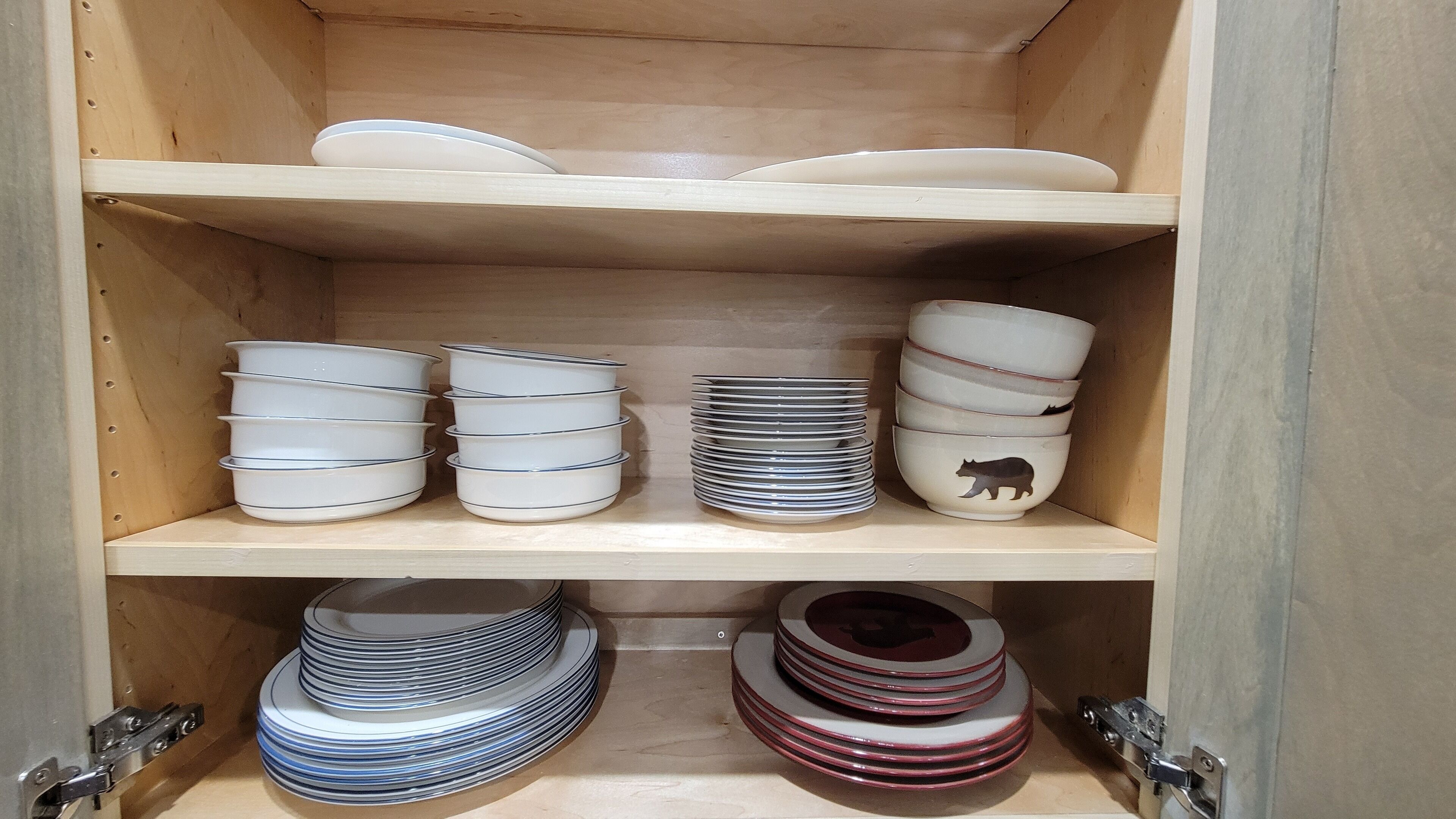 A wooden cabinet with shelves holding various ceramic dishes.