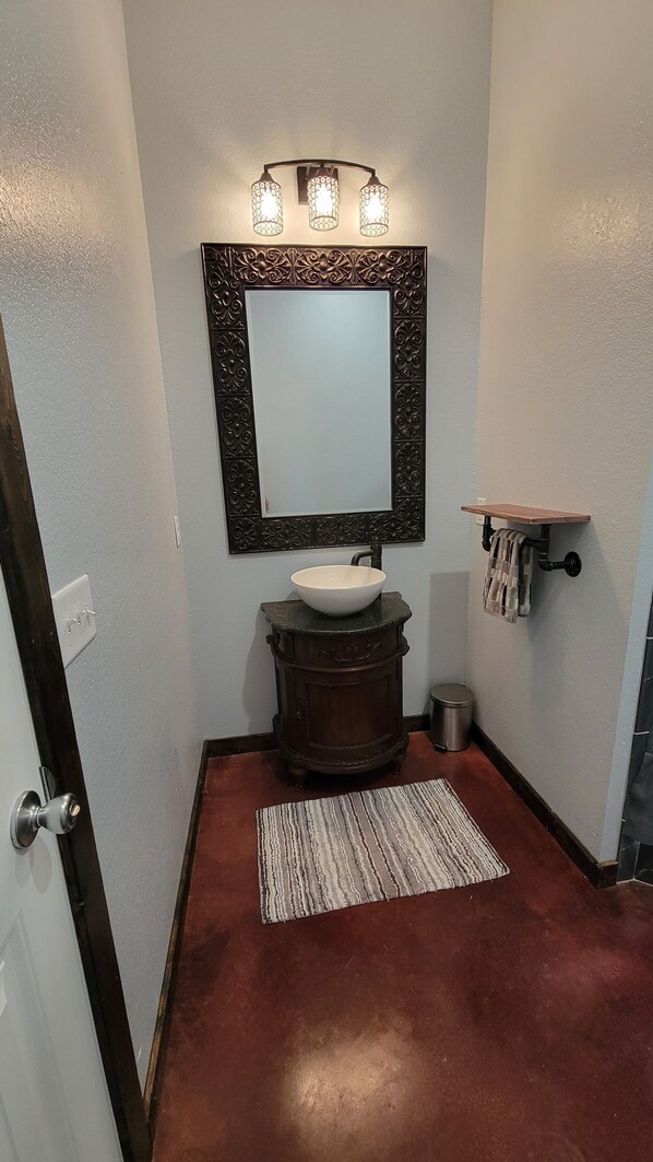 Une salle de bain comprenant un meuble-lavabo, un évier, un miroir avec éclairage, un porte-serviettes et un tapis.