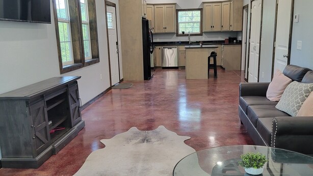 A spacious living area with a glass coffee table, a leather sofa, and a stone fireplace. - Cozy cabin 16 miles from Razorback Stadium great for game weekends. No pets. (Elkins)
