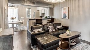 Un salon moderne avec un canapé d’angle en cuir, une table basse et un lustre.