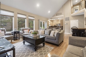 Relax in this spacious living room with a high ceiling, comfortable sofa, and dining area.