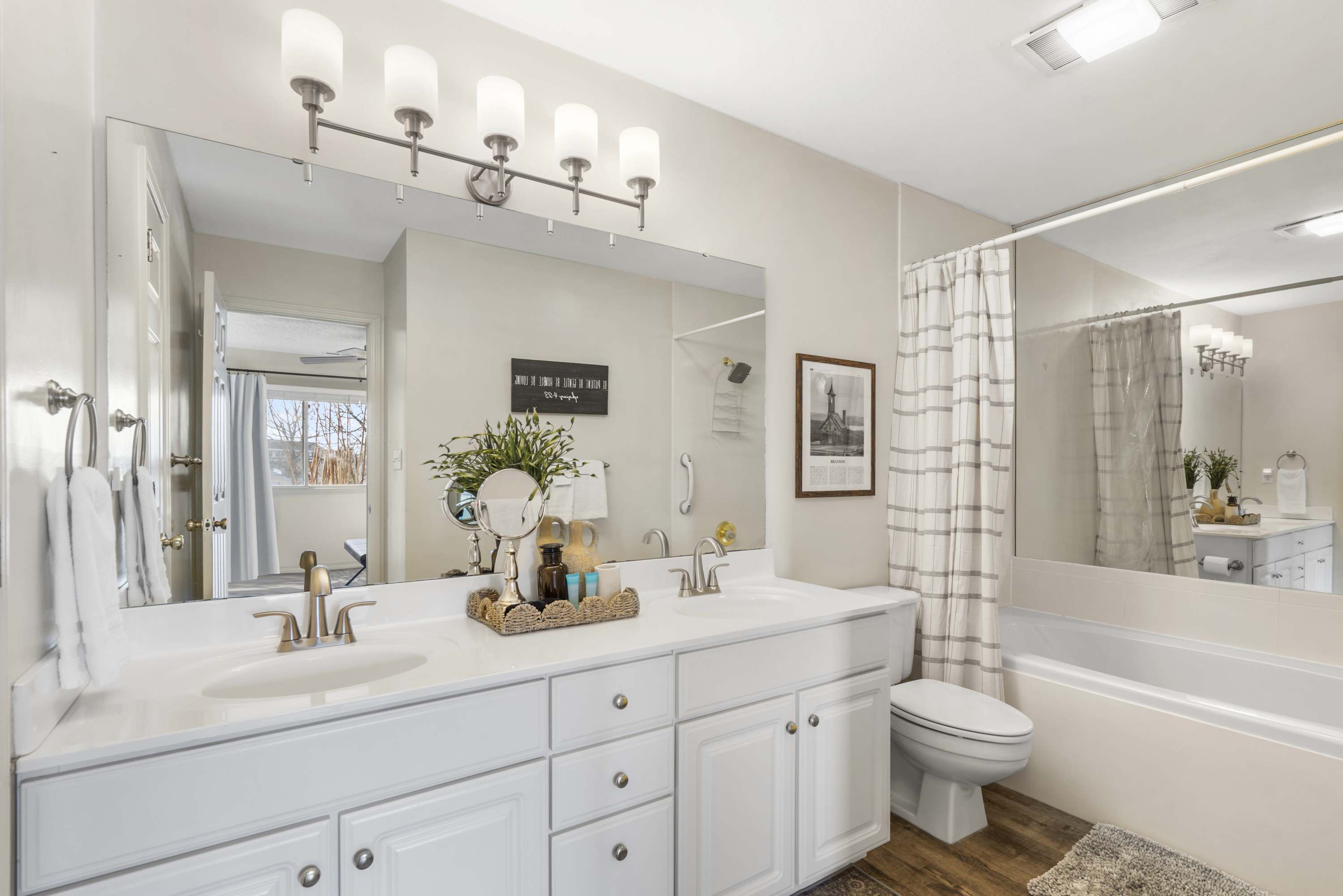 A modern bathroom with a large mirror, white vanity, and a toilet.