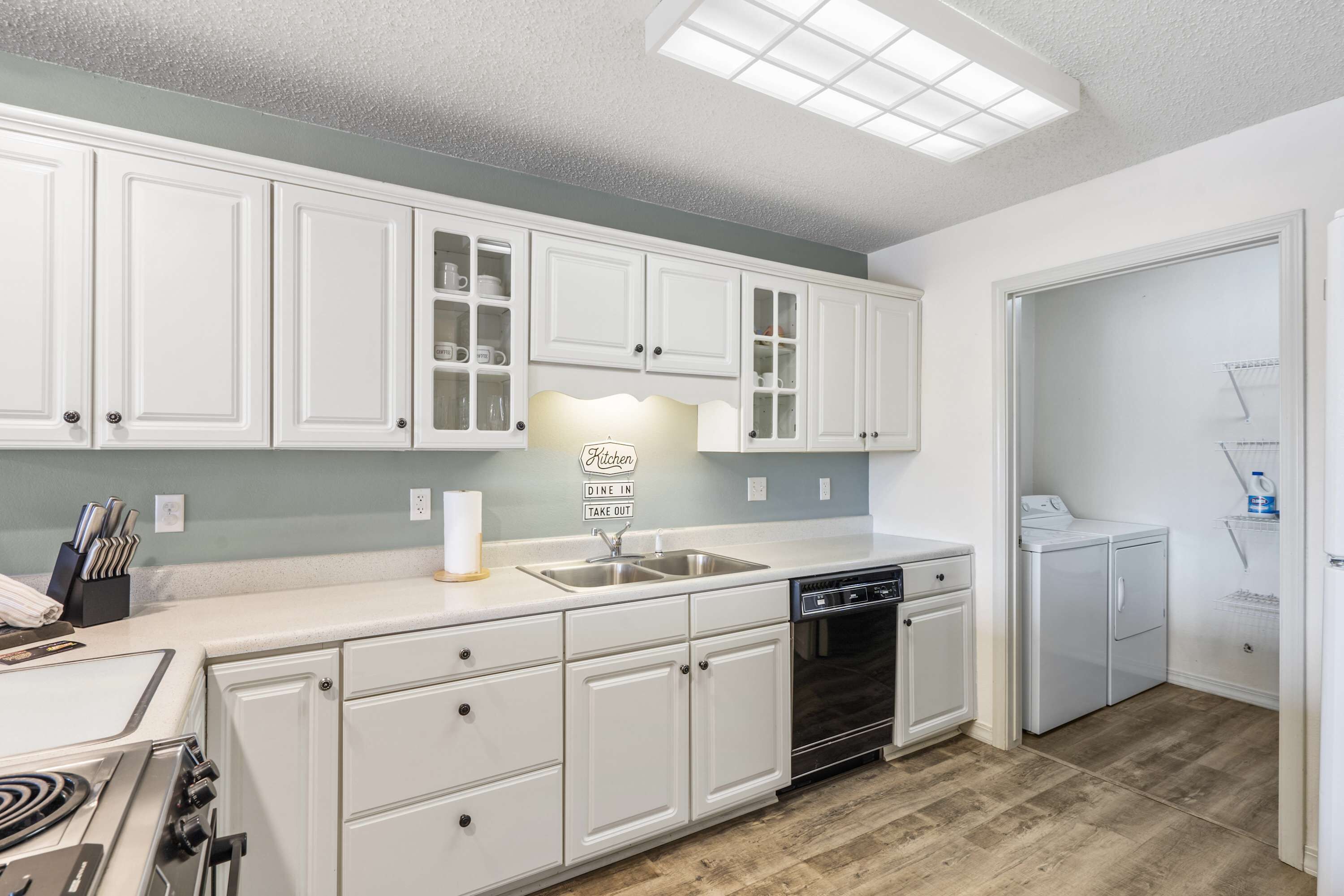 A modern kitchen with white cabinetry, a built-in dishwasher, and a countertop with a sink.
