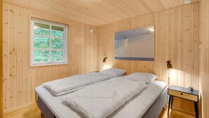Een kamer met houten lambrisering, een bed, een raam, een poster en een nachtkastje.