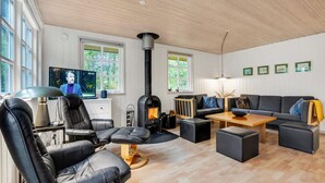 Een moderne woonkamer met een open haard, lederen zitmeubels, een televisie en lijstwerken aan de wanden.