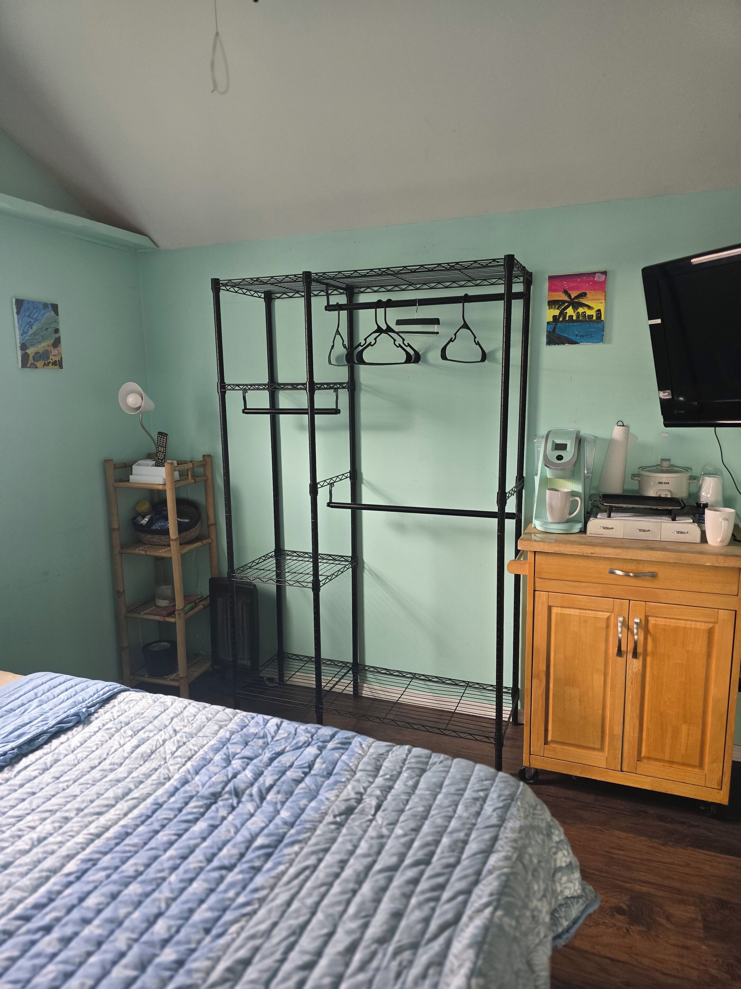 Ein Schlafzimmer mit einem Bett, einem Holzschrank, einem Metallregal und einem Fernseher.