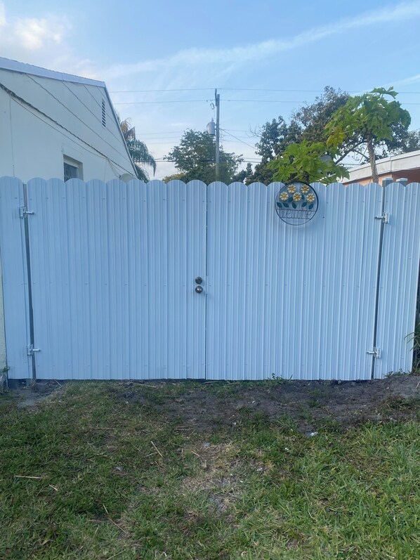 A corrugated metal fence with a "Welcome" sign and a circular emblem.
