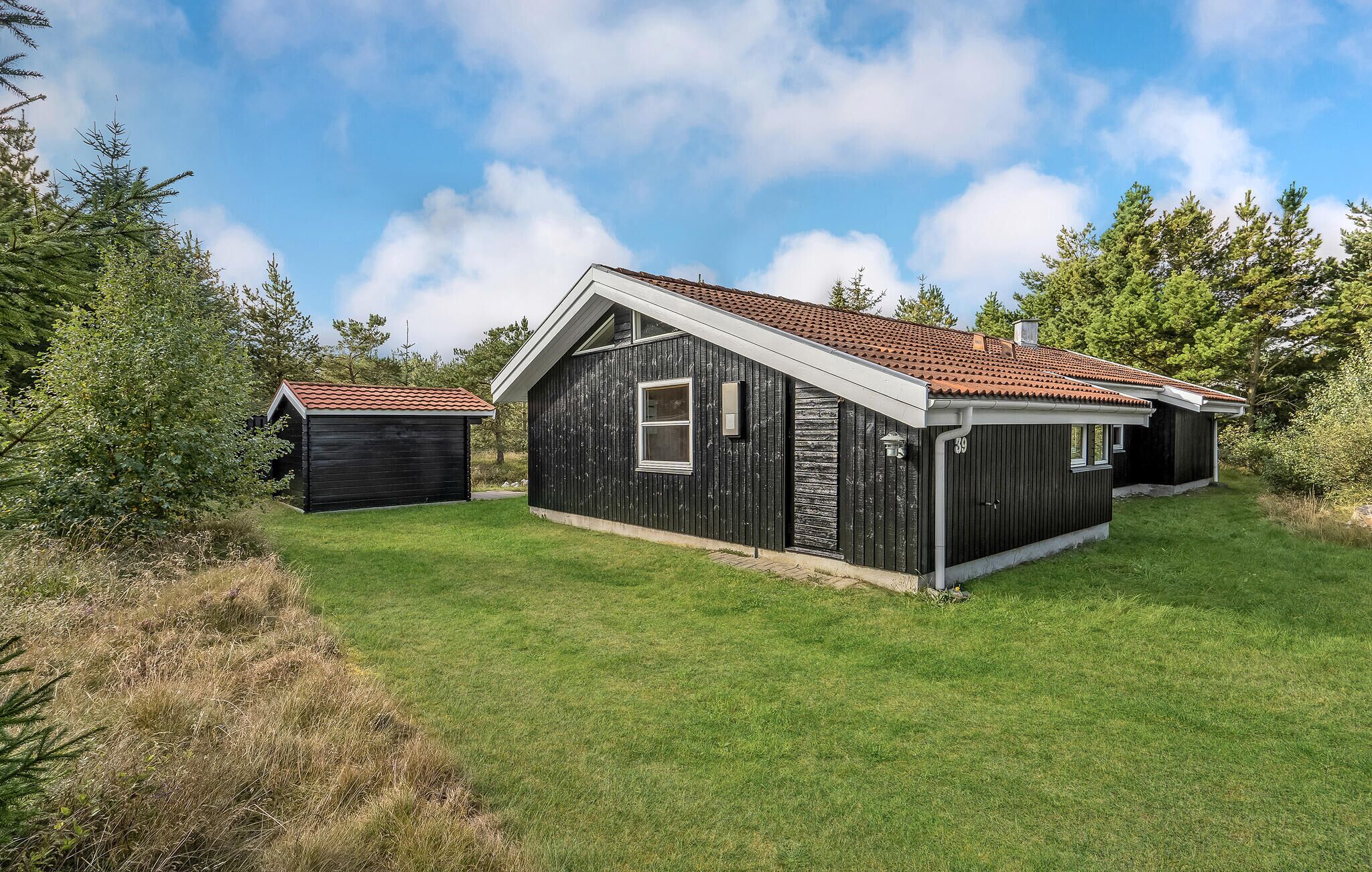 A two-story house with a red-tiled roof, a small attached garage, and a well-maintained lawn.