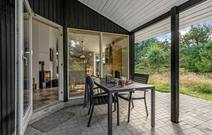 Enjoy al fresco dining in this outdoor space with a wooden table and chairs, a bench, and a cozy fireplace area.