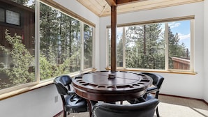 A round wooden table with four chairs in a room with large windows overlooking a forest. - Hall Court Manor - Hot Tub, Pet Friendly, Pool Table! (Stateline)