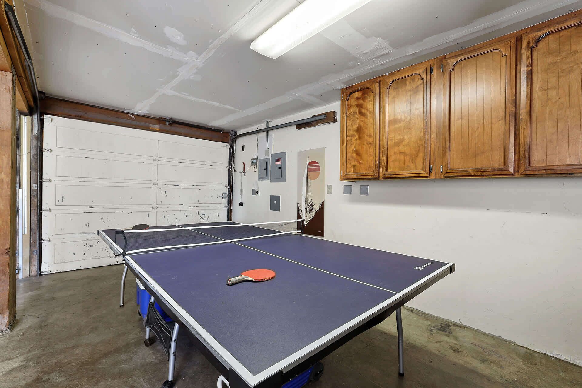 Une table de ping-pong dans une pièce dotée de meubles en bois et d’une porte blanche.