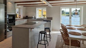 A modern kitchen with a central island, bar stools, and a dining table with woven placemats.