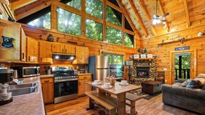 Een chalet met houten inrichting, een stenen openhaard en een eethoek met een bank.