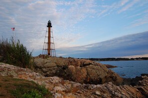Un phare sur une côte rocheuse, sous un ciel dégagé.