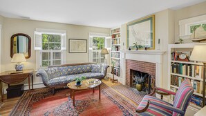A cozy living room with a fireplace, a bookshelf, and a patterned sofa.