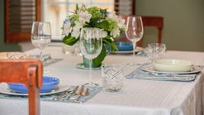 A dining table set with clear glassware, blue and white plates, and a vase with flowers.