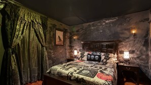 A bedroom with a wooden bed, patterned bedding, a dark headboard, and two bedside lamps. - The Warlock House (Salem)