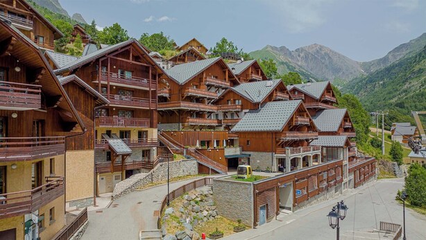 A cluster of wooden chalets with balconies, set against a mountainous backdrop. - Centre-ville! Studio pour 4 + proche des remontées (Vaujany)