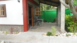 A covered outdoor area with a table and chairs, surrounded by plants and a green fence. - Strandhaus am Meer, Langzeitmiete 485 Euro + Strom 30 Tg (San Fernando)