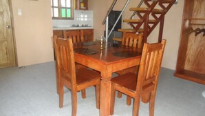 A dining area with a wooden table and chairs, a kitchen in the background, and a wooden staircase. - Strandhaus am Meer, Langzeitmiete 485 Euro + Strom 30 Tg (San Fernando)