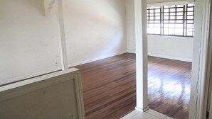 Una habitación con piso de madera, paredes blancas y una ventana con diseño de cuadrícula.