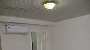 Una habitación con una puerta blanca, un equipo de aire acondicionado blanco y una alfombra marrón.