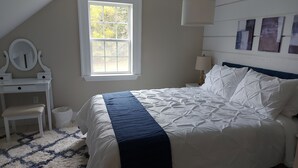 A bedroom with a bed, a dresser, a mirror, and a window. - Cozy Harbour House - Scenic-relaxing-waterfront (Municipality of the District of Guysborough)