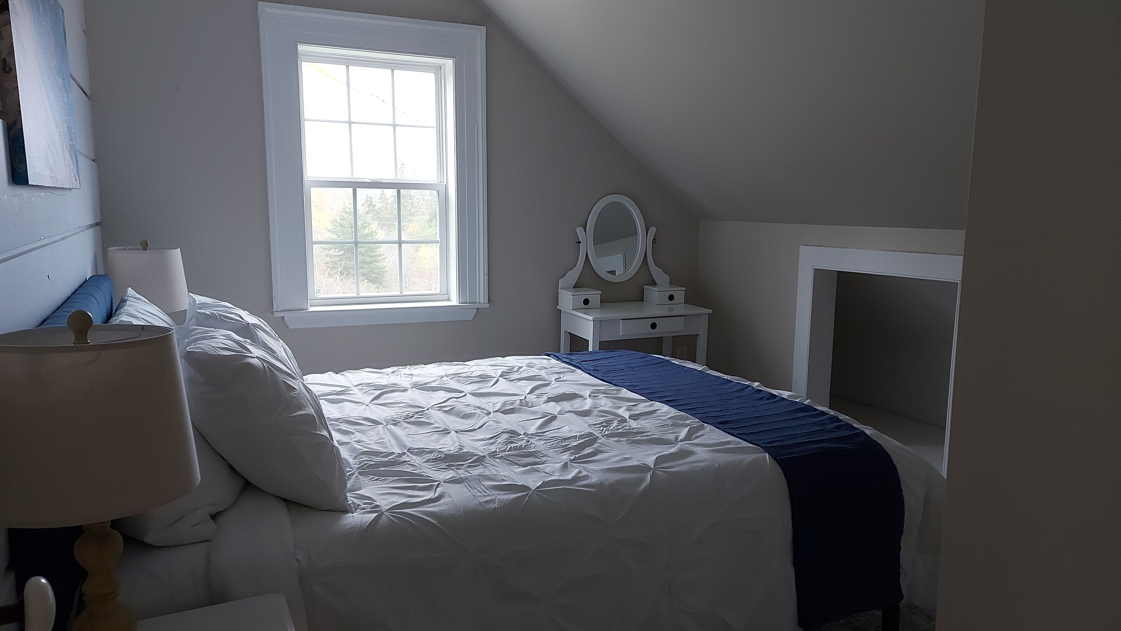 Une chambre à coucher avec un lit, une table de chevet, une commode avec un miroir et une fenêtre.