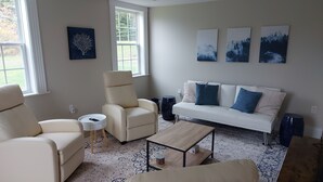 A living room with a white sofa, two armchairs, a coffee table, and artwork on the wall. - Cozy Harbour House - Scenic-relaxing-waterfront (Municipality of the District of Guysborough)