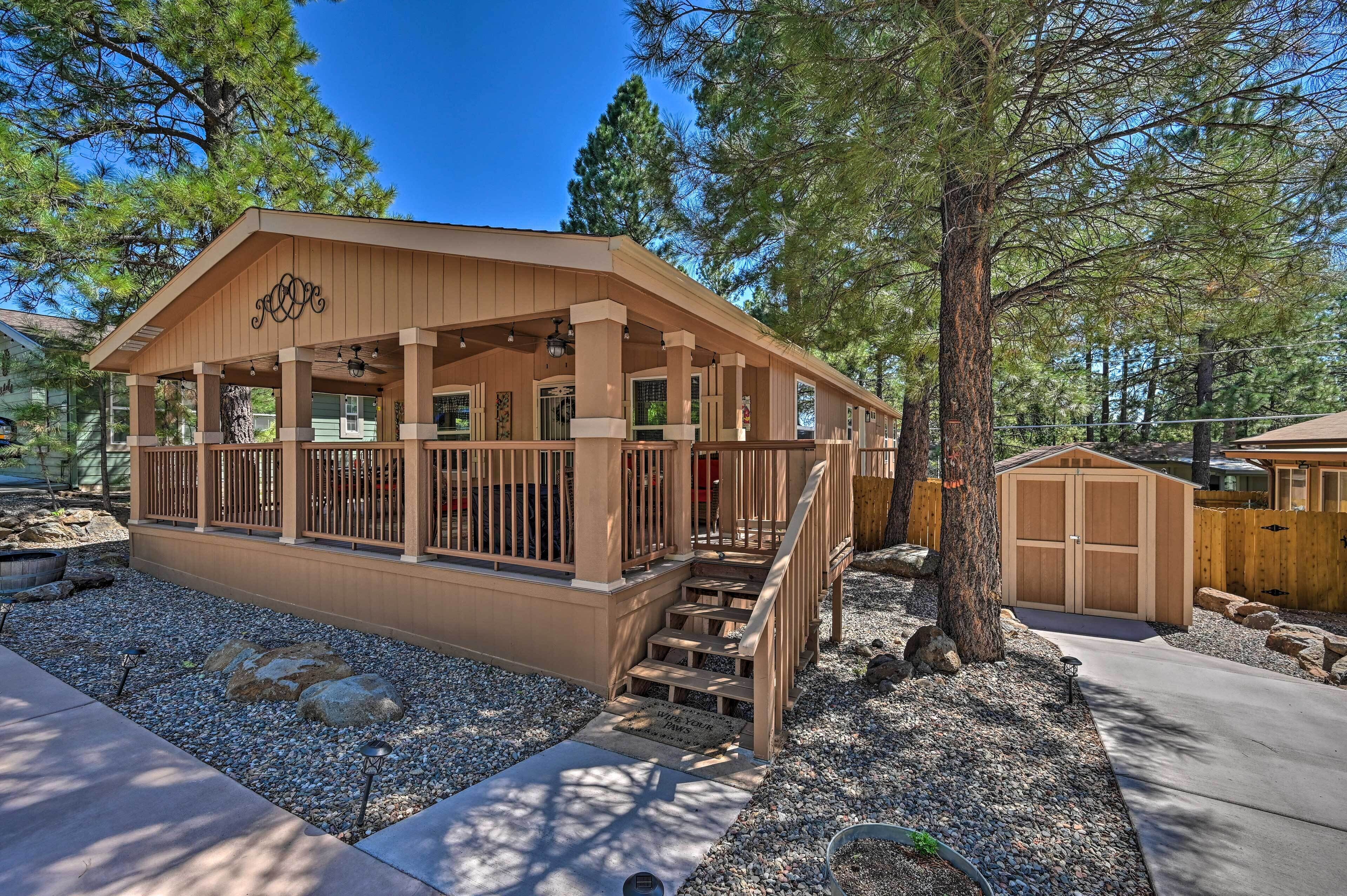 A wooden cabin with a porch, a garage, and a well-maintained gravel driveway.
