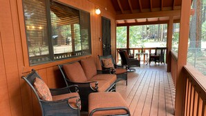 Eine überdachte Veranda mit Korbmöbeln und einer Holzterrasse.