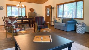 Ein geräumiges Wohnzimmer mit Holzboden, einem Esstisch, einem blauen Sofa und einem Schachbrett.