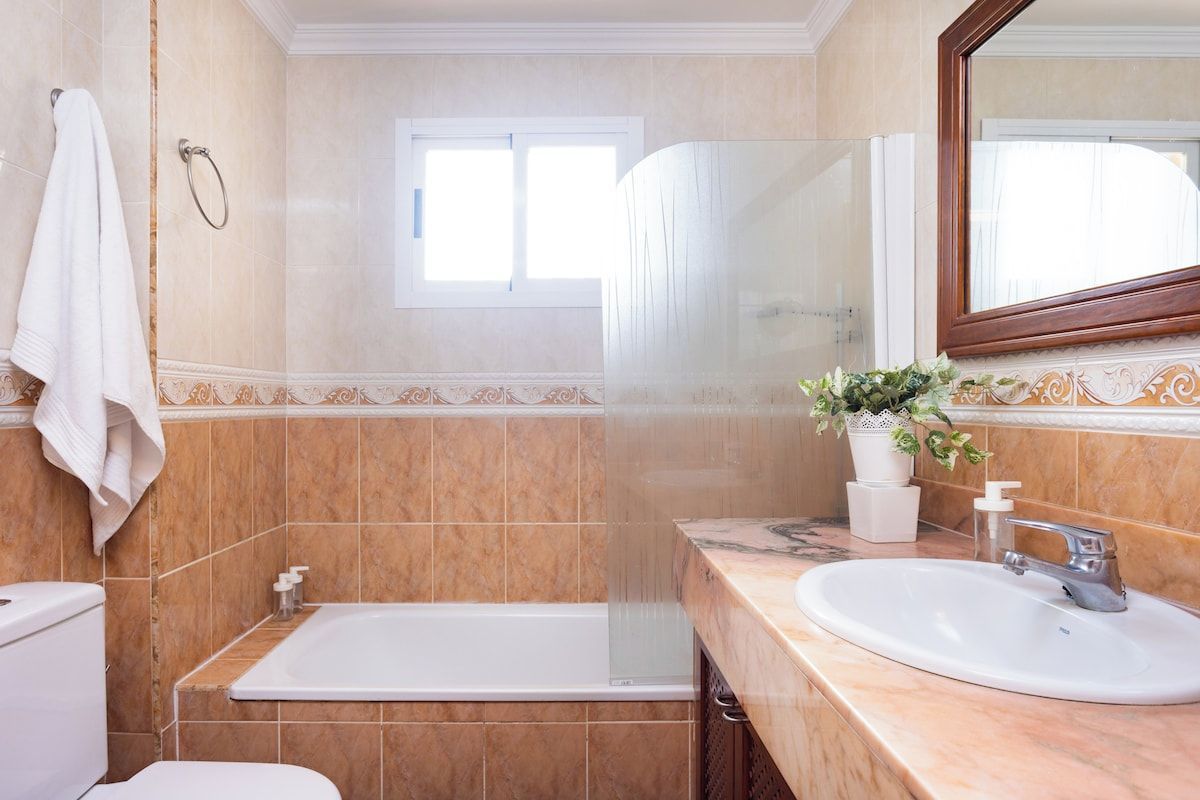 A bathroom with a bathtub, a sink, a toilet, and a window.