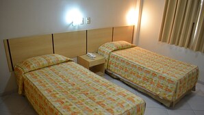 Habitación de hotel con dos camas individuales, una mesita de noche con teléfono y una lámpara de pared.