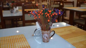 Una mesa de comedor con un jarrón decorativo de flores y una taza de café.
