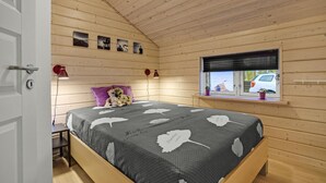 A cozy wooden cabin bedroom with a bed, a window with a view of a car, and a small table with a lamp. - Awesome home in ørsted with WiFi (Ørsted)