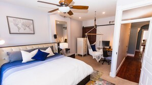 Une chambre à coucher avec un grand lit, un ventilateur de plafond, une carte du monde, un bureau et une chaise.