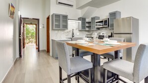 Una cucina moderna con mobili grigi, un frigorifero in acciaio inox e un tavolo da pranzo in legno con quattro sedie grigie.