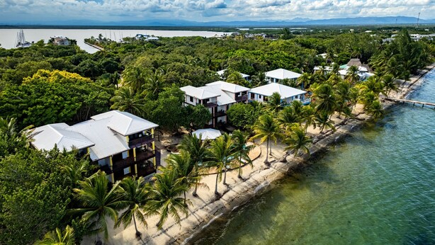 Una località balneare con diversi edifici in stile bungalow, una spiaggia sabbiosa e una vista limpida sull'oceano.