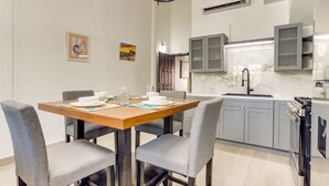 Una cucina moderna con mobili grigi, un piano di lavoro in marmo e un'area pranzo con tavolo in legno e sedie grigie.