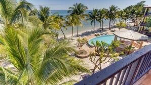 Un complexe hôtelier doté d’une piscine, de palmiers et offrant une vue sur la plage.