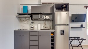 Une cuisine moderne avec des meubles gris, un four à micro-ondes encastré, un grille-pain et un réfrigérateur en acier inoxydable.