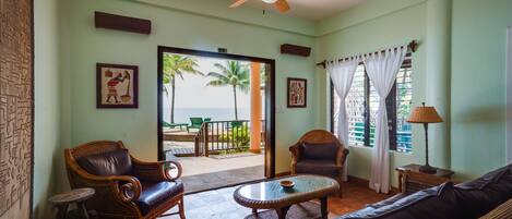 A room with wicker furniture, a ceiling fan, and a view of the beach.